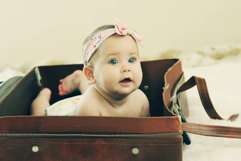 bébé fille allongée dans une valise vintage